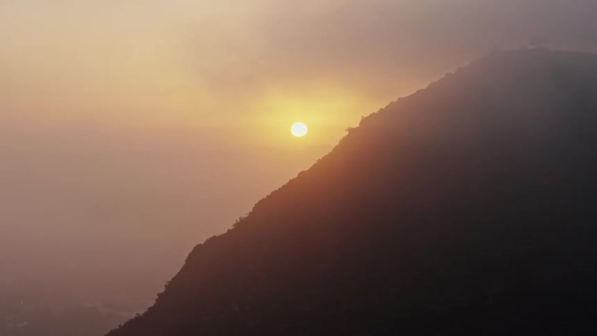 Aerial footage of the sun setting behind the Hollywood Hills and shining through the marine layer