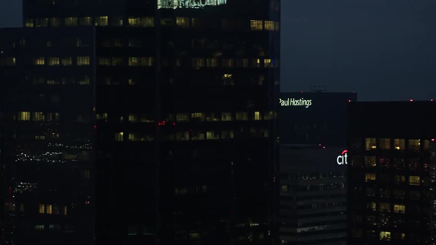 Captivating 4K aerial footage of towering skyscrapers with glowing windows during a cloudy twilight in the heart of Downtown Los Angeles