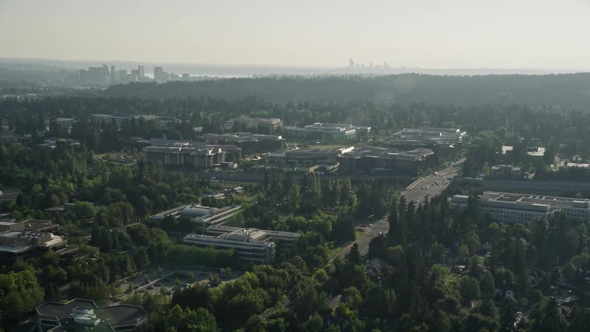 Aerial footage capturing a reverse view of Microsoft Headquarters in Redmond Washington showcasing the office complex set against the hazy backdrop of the Pacific Northwest