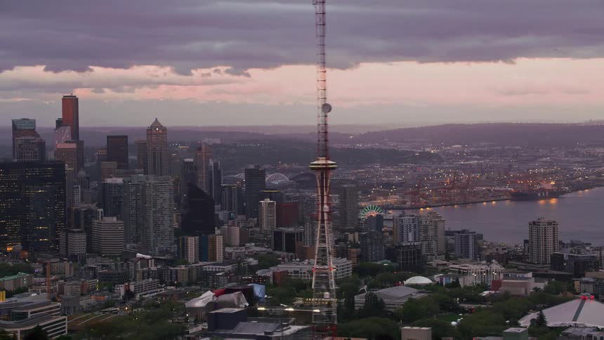 An aerial view of a city skyline along a waterfront harbor at dusk