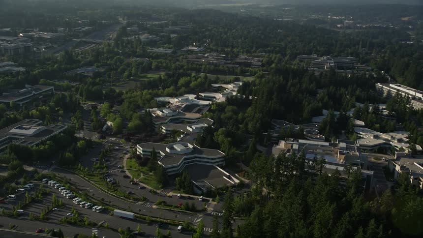 Aerial footage of the Microsoft Headquarters office complex in Redmond Washington captured during a hazy day with a wide-angle and side view flyby
