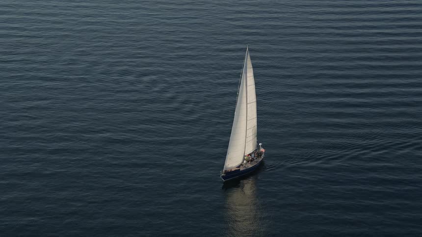 Sailboat sailing on Elliott Bay in Seattle Washington with people standing on board