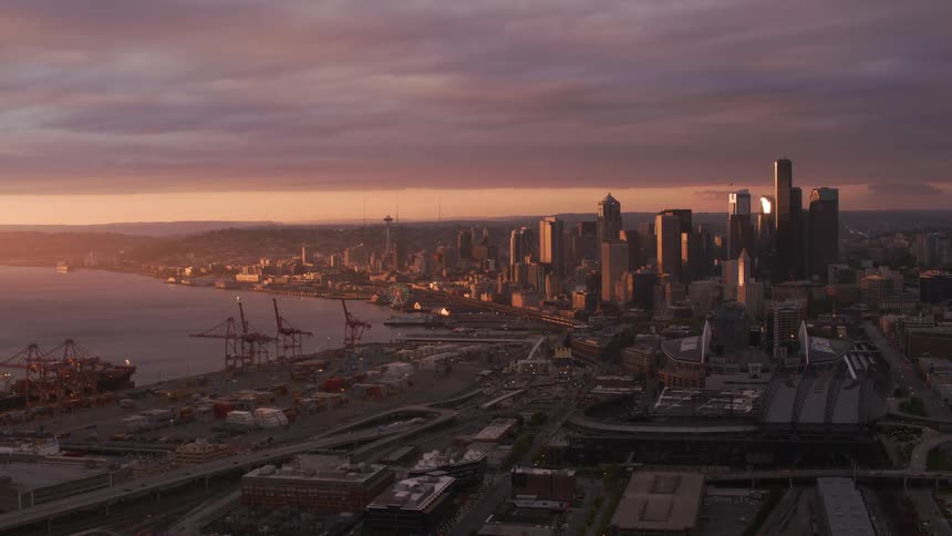 Freighter sits at dock near city downtown under a red tinted overcast sky