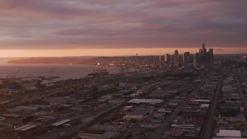 Traffic moves along highway near waterfront on the way to city under red sky
