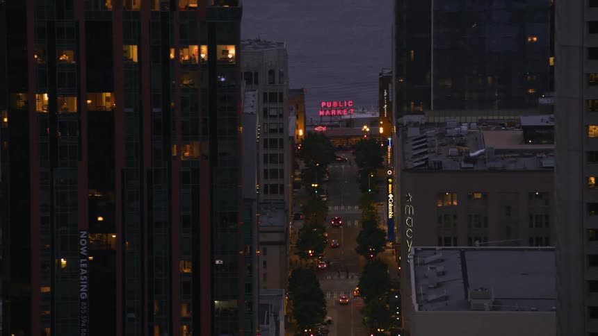 Traffic moves along street toward coast between buildings at night
