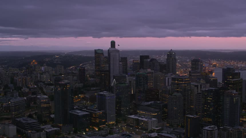 Purple gray clouds in a red sky hover over misty coastal city