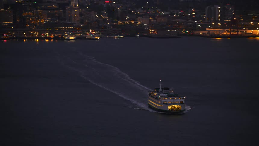 Aerial view of ferryboat sailing off the coast with skyline in the background in the evening