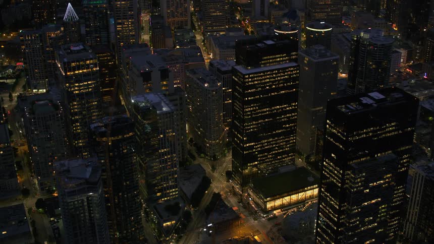 Traffic drives along brightly lit streets separating downtown skyscrapers