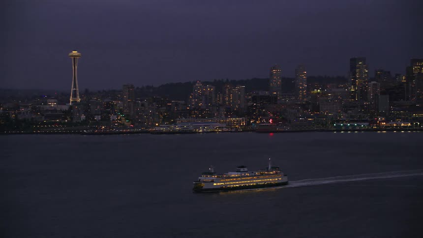 Ferryboat sailing away from the coastline while showcasing the city skyline in the background during the evening