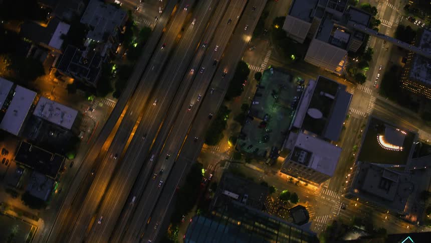 Traffic flows down controlled access highway through downtown at night
