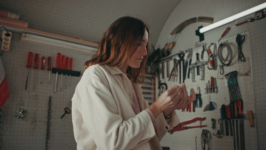 Woman works on craft at workbench near hand tools