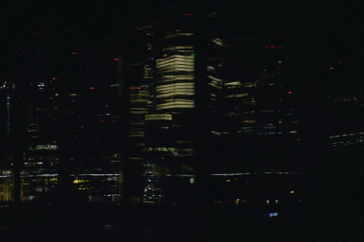 A view of a tall urban building reflected in glass at night