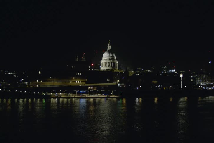 A static shot of a white domed building lit up along the waterfront