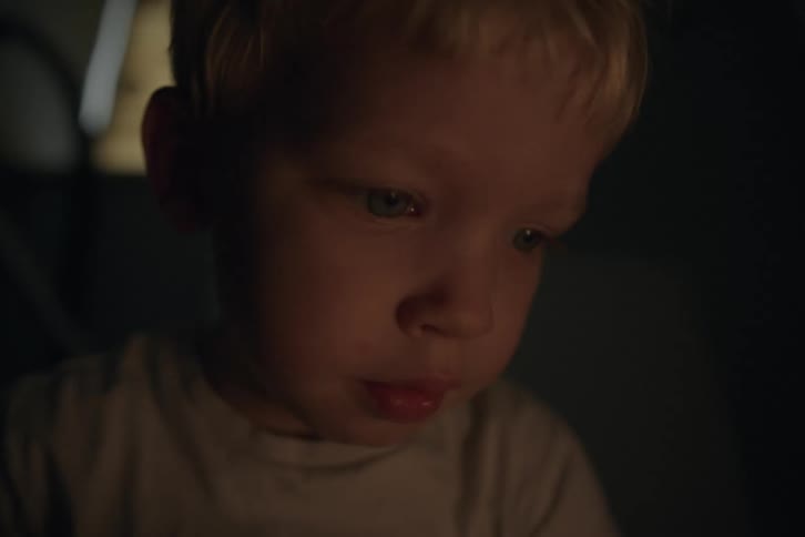Blonde boy looks around in dark room