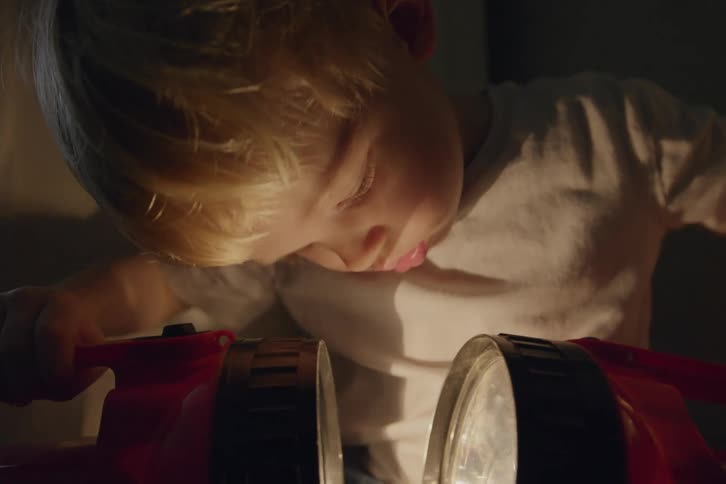 A child is playing with two flashlights