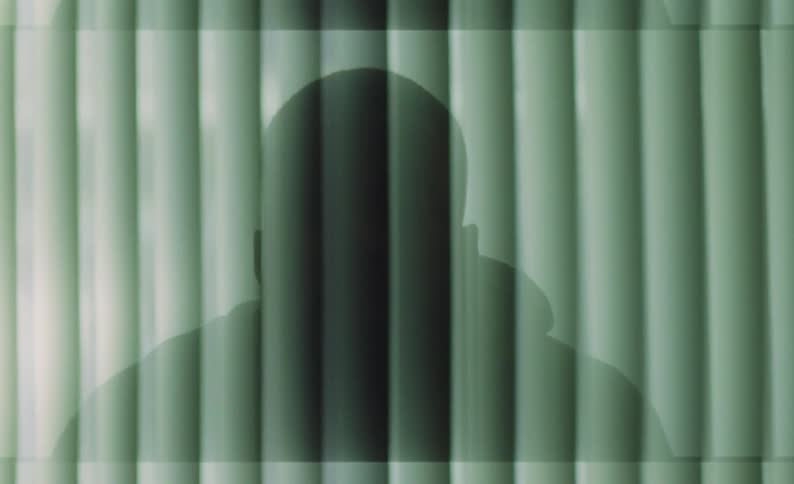 The silhouette and shadow of a man sitting as computer animation changes the screen