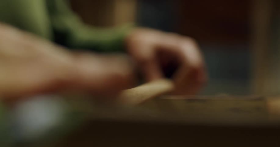 Shot of male hands with one of them rubbing a stick on top of a table while the other one holds it form