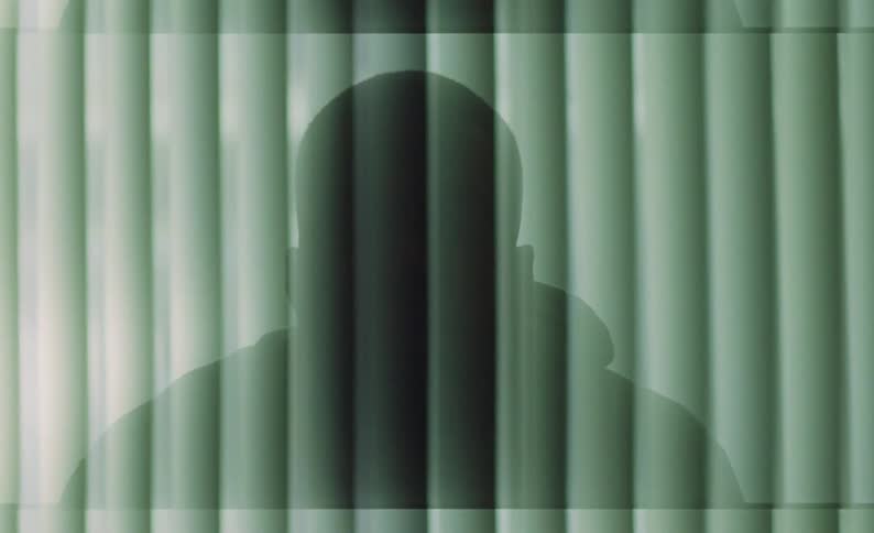 Male silhouette sitting still against a textured background with moving lights passing over it