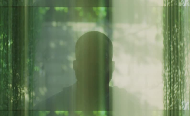 Silhouette of a mans face wearing a hoodie with moving lights occluding him