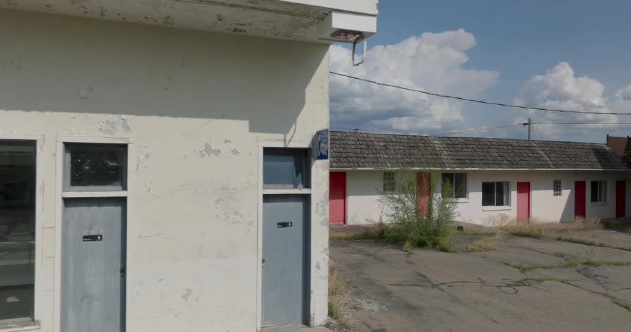Traverse along the exterior wall of a dilapidated motel office and gift shop