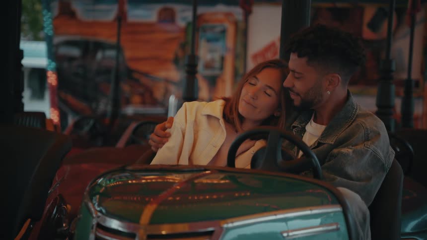 A woman rests her head on her partners shoulder in a bumper car