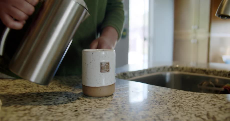 Man pours coffee into mug on kitchen counter