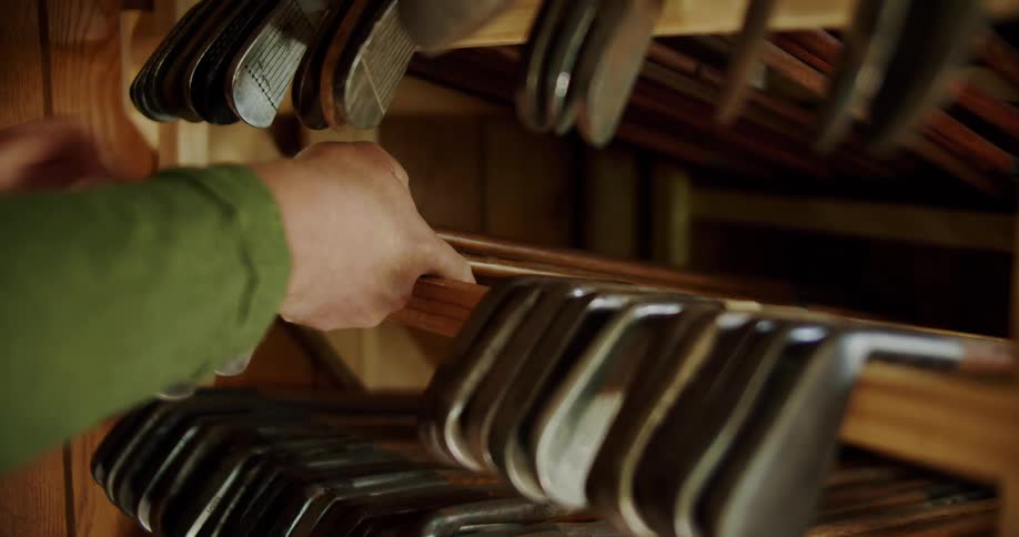 White male hands arranging golf clubs