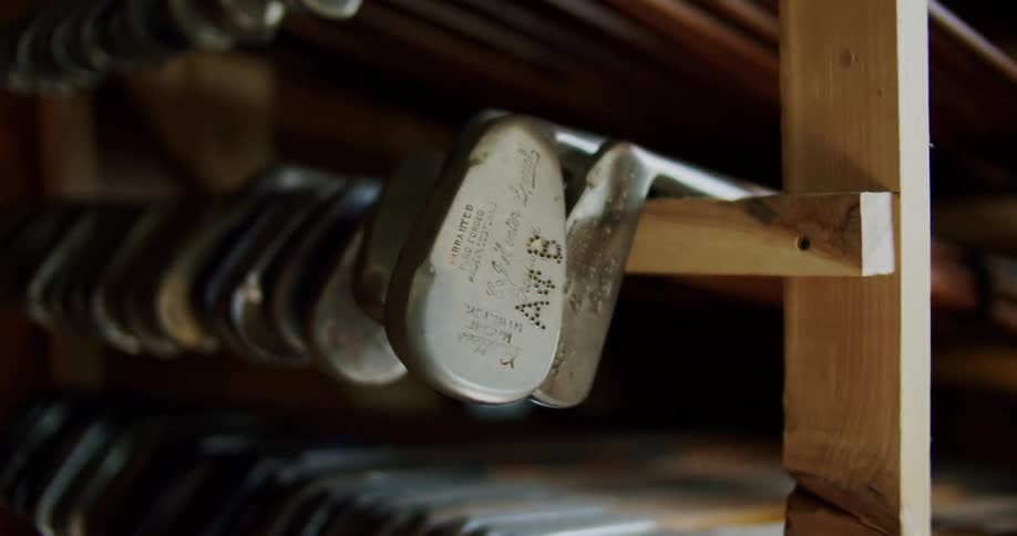 Several golf clubs occupy open wooden frame storage