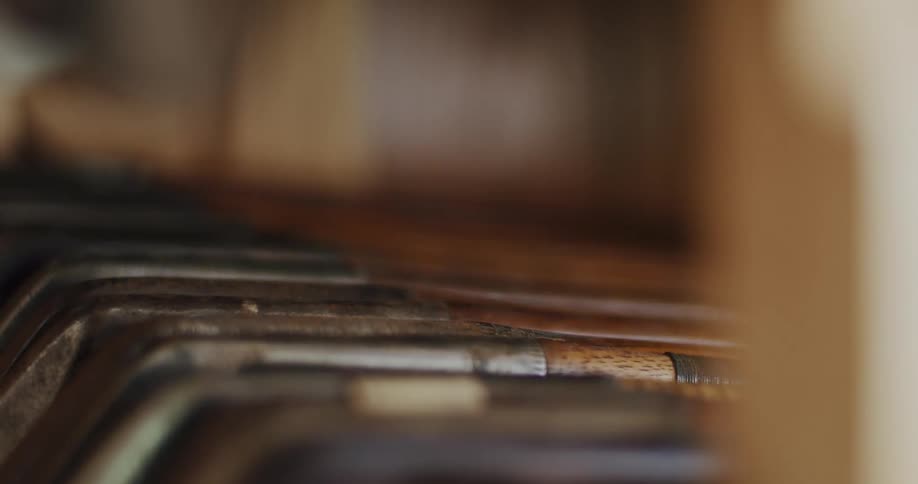 Multiple golf clubs lie in a row on open frame