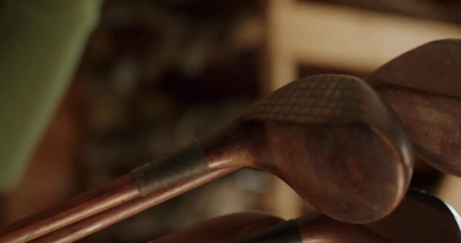 Golf clubs on a rack while and a close up of a person holding golf clubs in their hand
