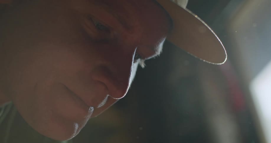 A man smiles while looking down in a garage