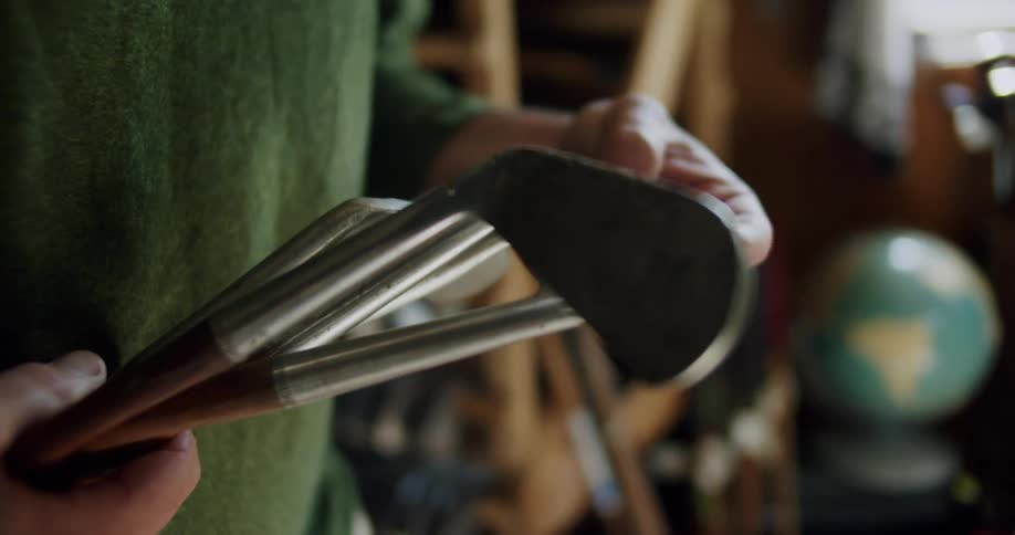 Man with green sweatshirt checks golf clubs