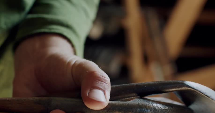 A hand touching and examining the heads of several golf clubs