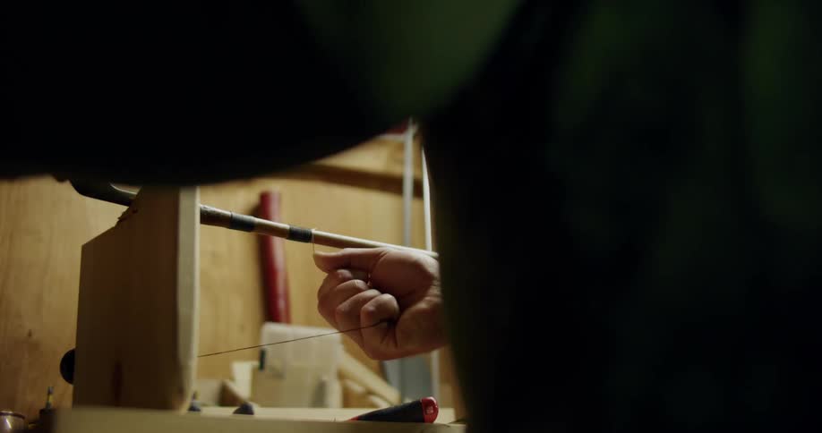 A close up of a person using wood working tools and spiraling a string around a rod