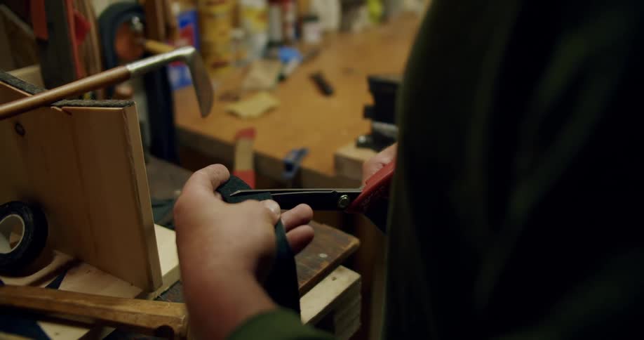 Man clips strip while standing in workshop near golf club
