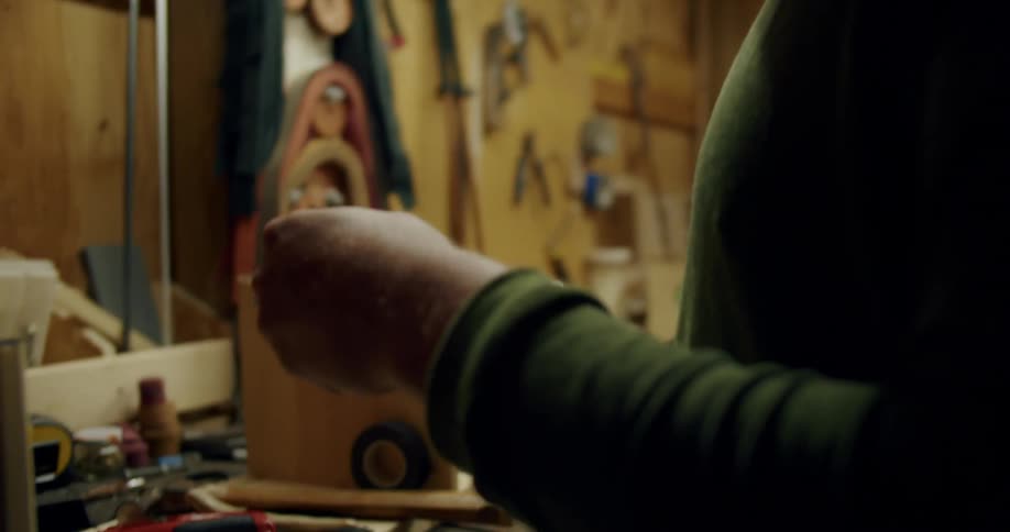 Man in workshop places handle to golf club on workbench