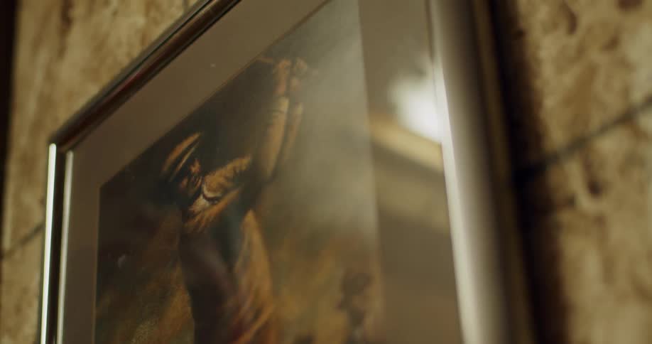 A close up of a picture in a frame on the wall of a man swinging a golf club