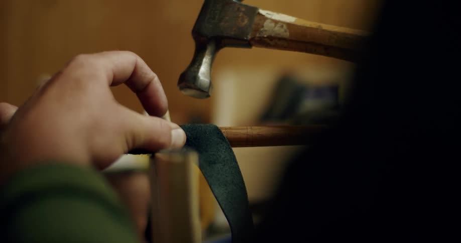 A close up of a person using a hammer to pound wood