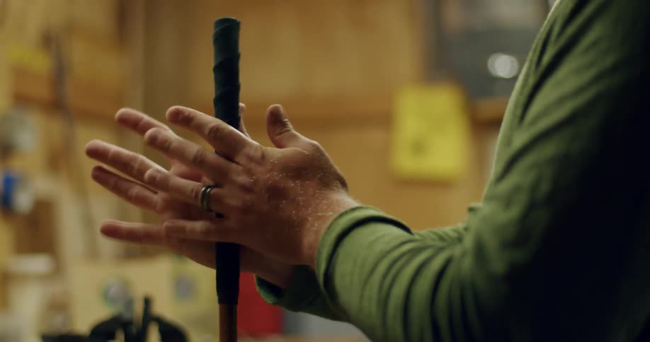 A man rolls a racket handle between the palms of his hands