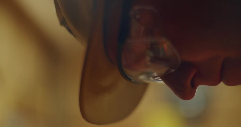 Man wearing hat and safety glasses focuses downward