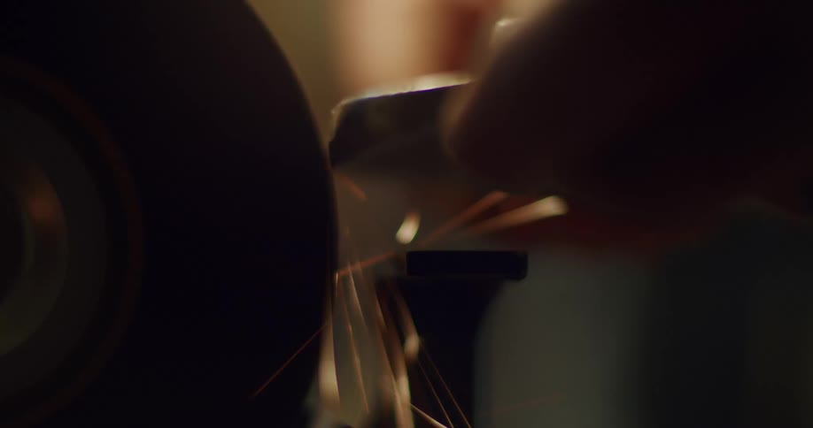 Shot of male hands working on a sharpening wheel with fire sparks flying around them