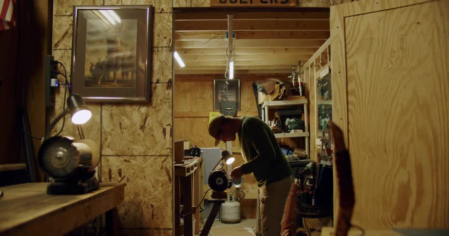 Man stands in workshop shaping metal with a grinder and creating sparks