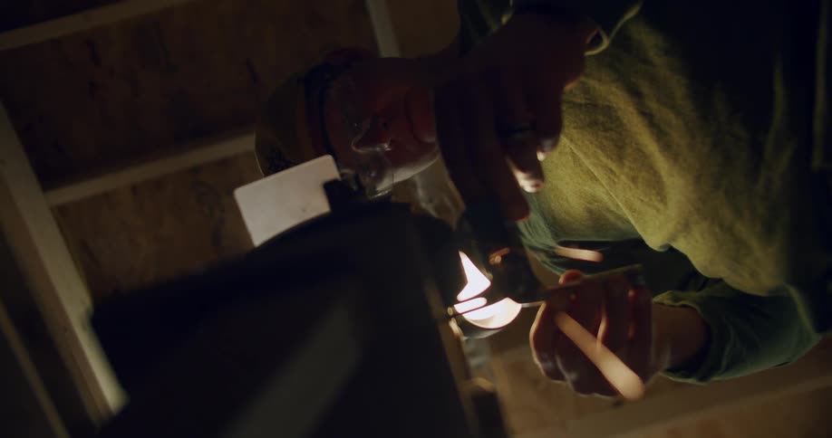 Man shapes head of golf club with grinder creating sparks