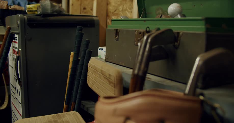 Sporting equipment including golf clubs sit in unfinished garage