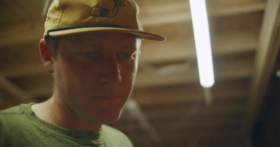 Man with yellow hat green shirt looks down at golf clubs