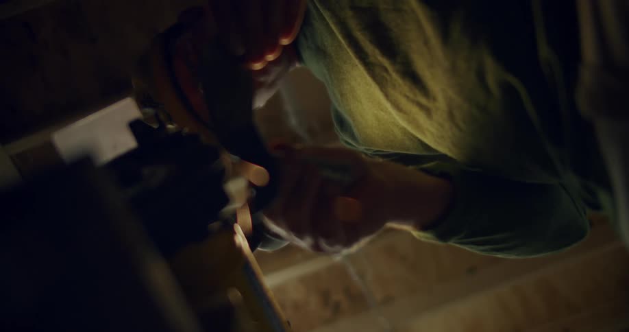 Sparks fly as a man holds a piece of metal to a tool