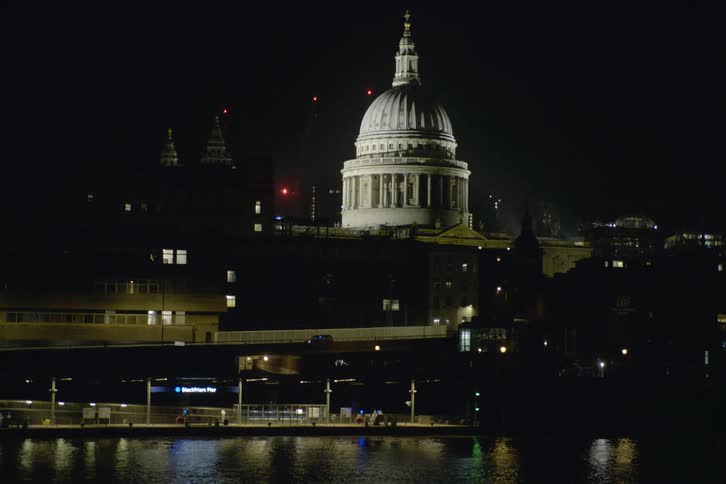 A shot of a domed white waterfront building lit up at night