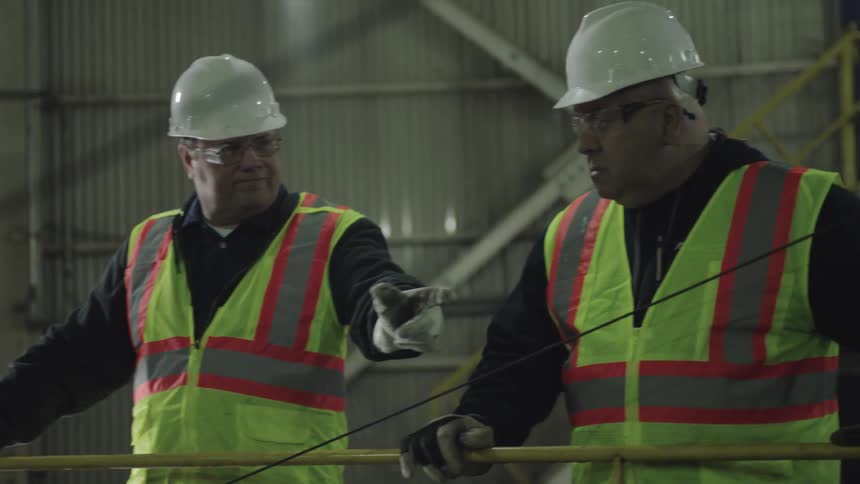 Construction workers looking and pointing at equipment in a warehouse