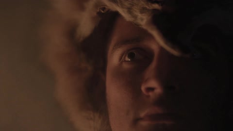 Man with animal pelt on his head staring off