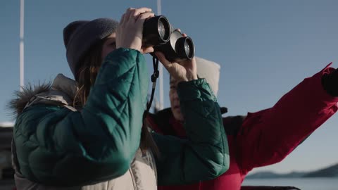 A man is pointing something out to a woman as they stand on a boat